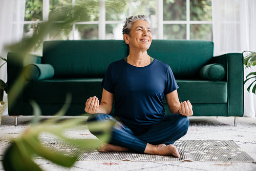 Yoga meditation for inner peace and mindfulness: Senior woman meditating in lotus position at home