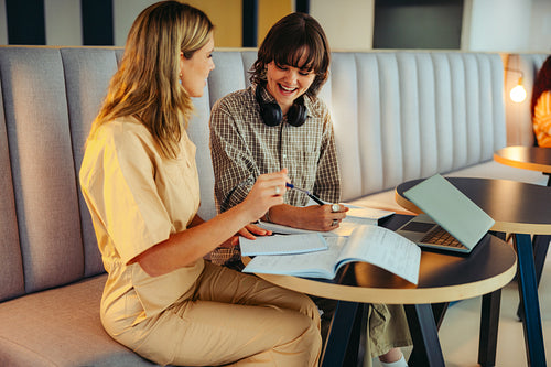 Joyful college classmates studying together in a modern campus lounge, discussing notes and collaborating on projects