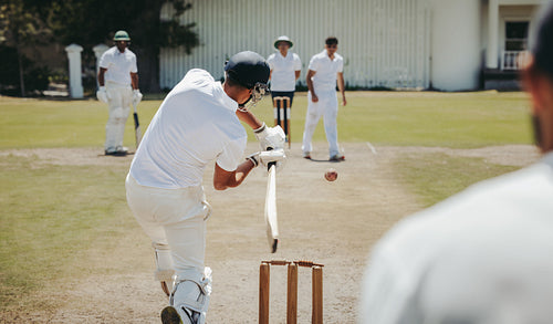 Cricket match with batsman hitting a fast ball on a sunny day