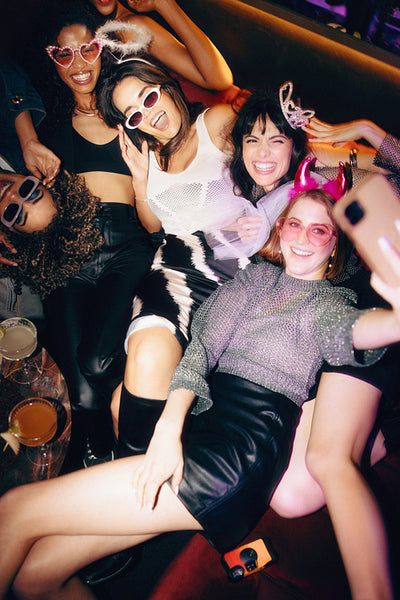 Group of friends having fun at a party with festive glasses and smiles