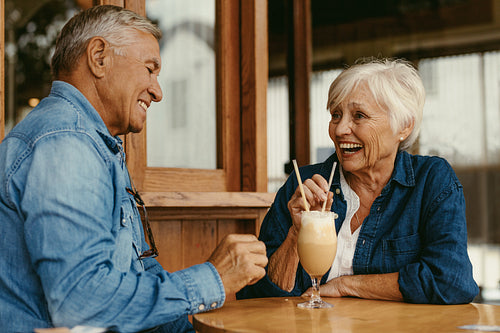 Cheerful senior couple sitting at table in cafe