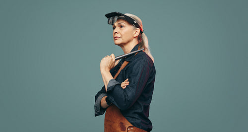 Mature goldsmith holding a ring mandrel in a studio