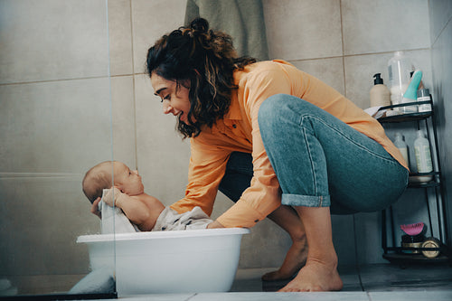 Mother bathes baby in tub during bath time