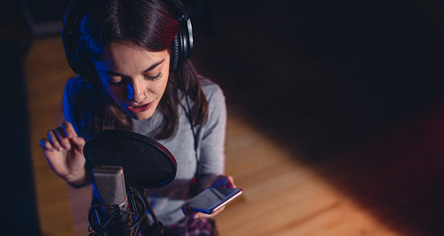 Female singer singing song in recording studio