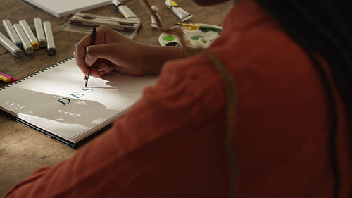 Creative young woman sketching the word “DESIGN” on a notebook