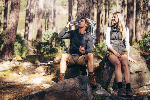 Hiking couple relaxing sitting on rocks during trekking