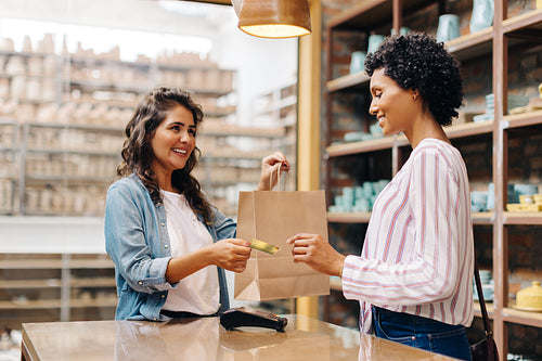 Happy young shop owner receiving a credit card from a customer