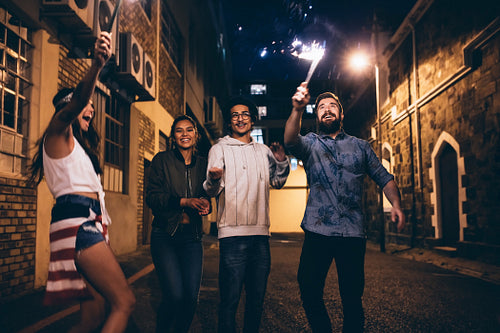 Young people playing with sparklers at night