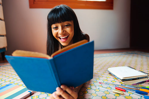 Young girl reading a book at home during leisure time