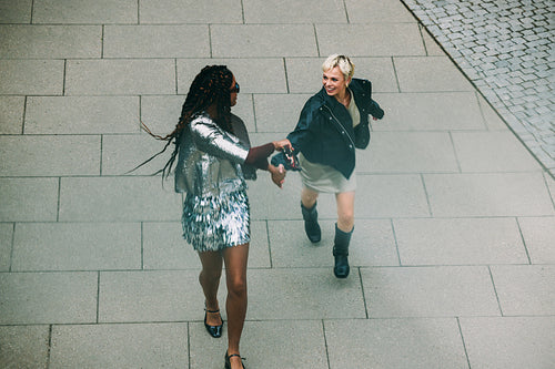 Friends walk hand in hand on a city plaza