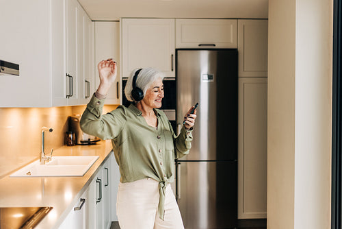 Cheerful senior woman dancing to her favourite music at home