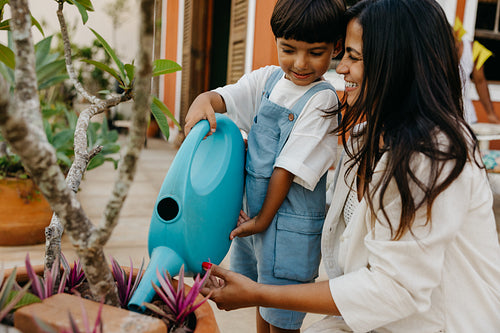 Mother and child watering plants together in the garden on a sunny day