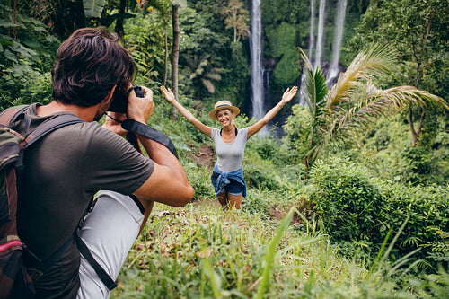 Photographer taking pictures of a woman by waterfall