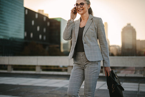 Businesswoman walking outdoors on city street with mobile phone