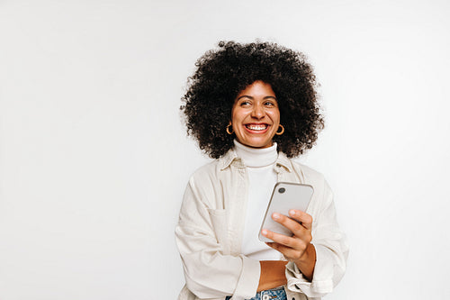 Happy young woman looking away while holding a smartphone