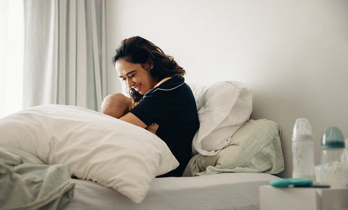 Mother breastfeeding baby in bedroom