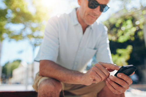 Senior man using cell phone outdoors