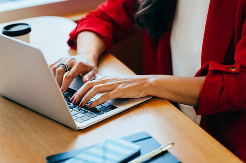 Woman typing on a laptop while wearing a red blazer at a desk