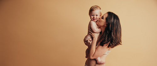 Mother kissing her cute smiling baby
