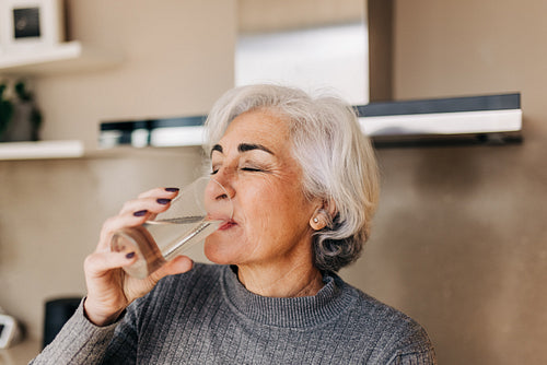 Elderly woman drinking fresh tap water at home