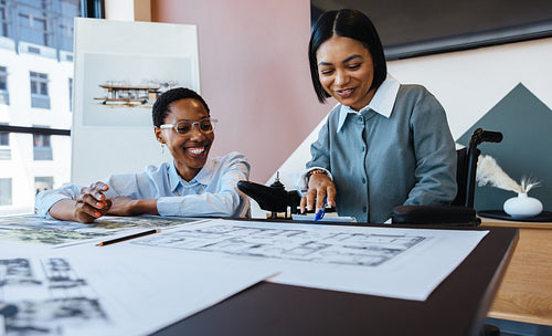 Two women working together on architectural plans in a creative office setting