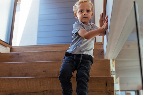 Little boy alone walking down stairs at home