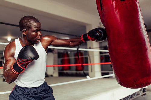 Fit African boxer practicing his punches at the gym