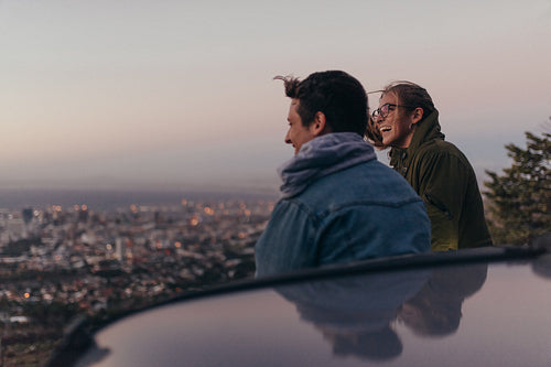 Smiling couple on a hilltop looking at the city below