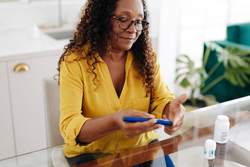 Senior woman controlling her blood sugar levels with an insulin injection