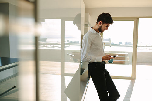 Businessman checking phone while having breakfast at home