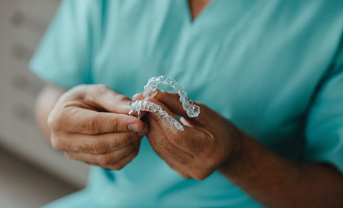 Dentist holding clear dental aligners for orthodontic treatment