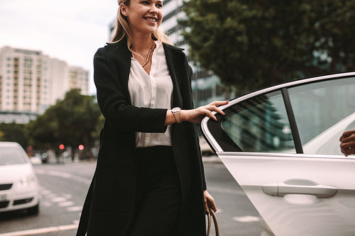 Smiling woman commuter getting out of a taxi