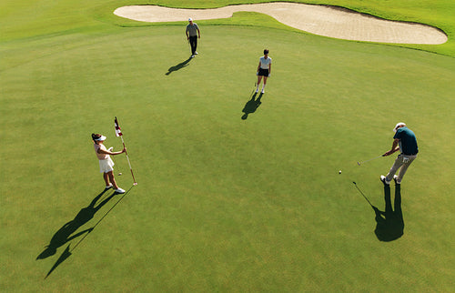 Aerial view of people playing golf on the green at a golf course