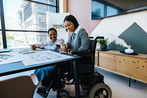 Two women working together on architectural plans in a modern office