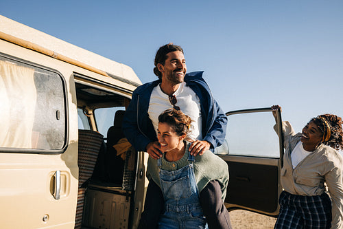A group of friends enjoy a playful road trip moment by a van