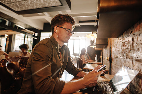 Casual businessman at cafe using cell phone