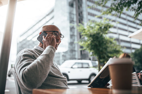 Businessman talking on mobile phone sitting at a restaurant.