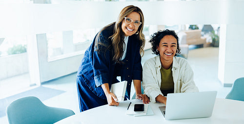 Two businesswomen work together at a laptop