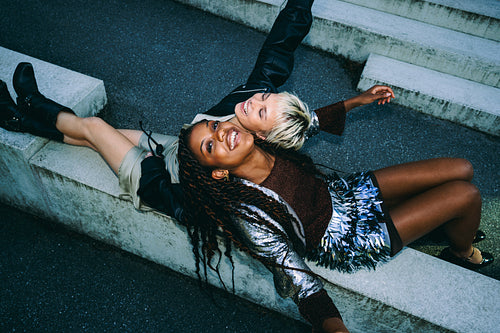 Young woman laughs with friend on concrete steps
