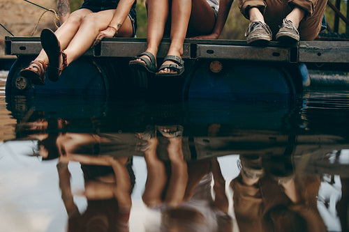 Friends sitting on a floating dock on a lake