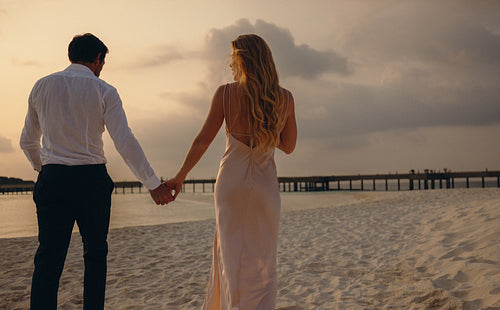 Young couple holding hands on a serene island beach at sunset