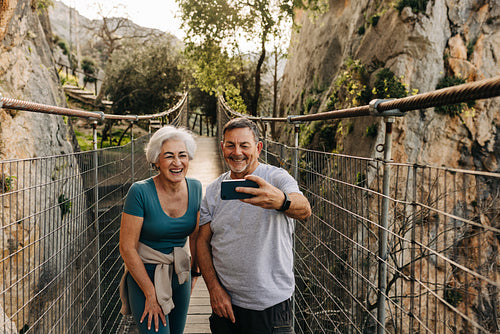 Smiling couple taking a selfie together on a bridge