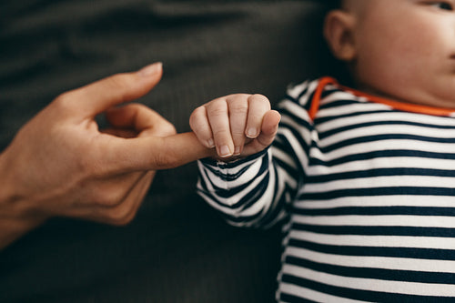 Close up of a baby holding the hand of his mother