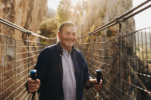 Cheerful senior man smiling at the camera while hiking outdoors