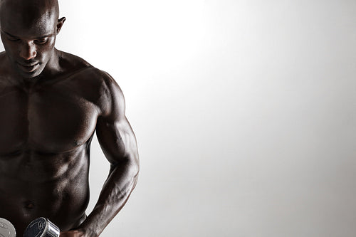Healthy muscular young man holding dumbbells