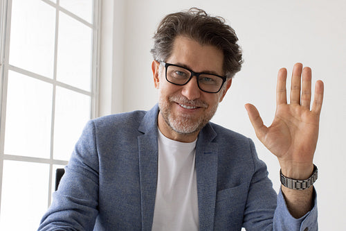 Senior business man waving to his colleagues on a video call