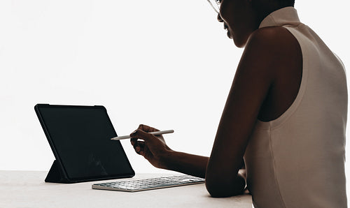 Professional woman using a stylus with a tablet and keyboard
