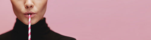 Close up of woman with straw on pink background
