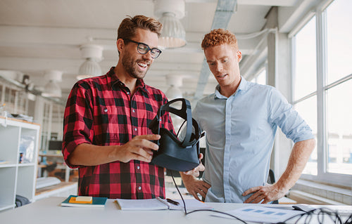 Happy young colleagues working on virtual reality device