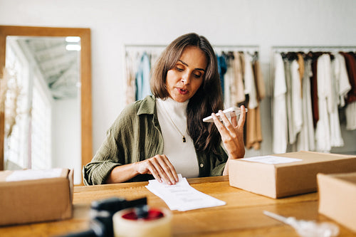 Ecommerce business owner talking on the phone while fulfilling clothing orders